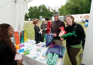 Photo de membres du personnel de l’Ordre à un kiosque au 39e Festival franco-ontarien. Ils rient avec des participants.