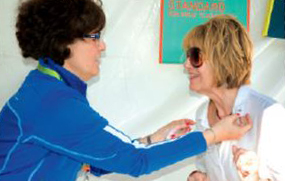 Photo d’un membre du personnel de l’Ordre au kiosque de l’Ordre au festival Word on the Street. Elle donne une épinglette EAO à un membre de l’Ordre.