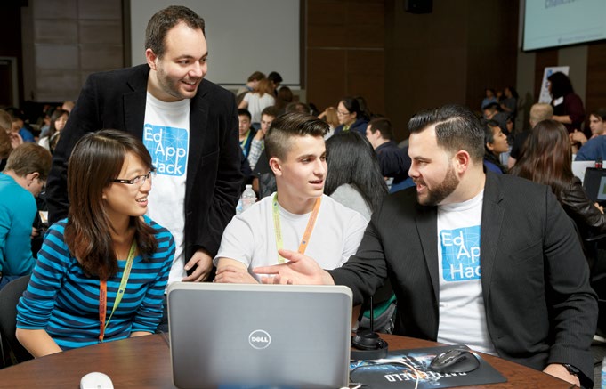 Photo de Joseph Romano, enseignant agréé de l’Ontario, et de Brandon Zoras, enseignant agréé de l’Ontario, occupés à discuter avec deux élèves de questions sur la programmation.
