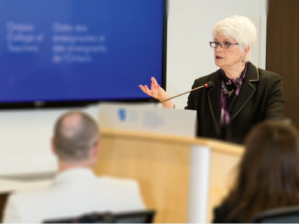 Photo de Liz Sandals, ministre de l’Éducation de l’Ontario, au podium. Elle parle du partenariat entre l’Ordre et le Ministère aux membres du conseil.