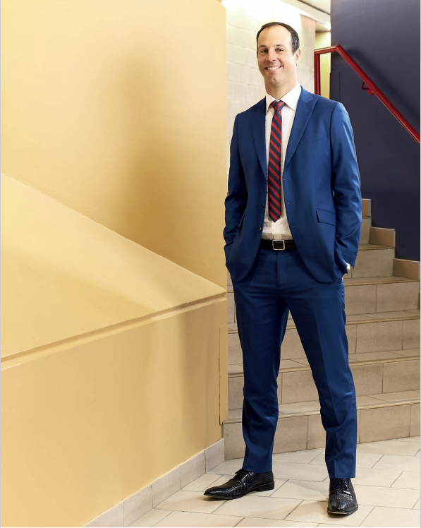 Photo de Jason Dupuis, enseignant agréé de l’Ontario, debout les mains dans les poches, près d’un escalier de l’école.