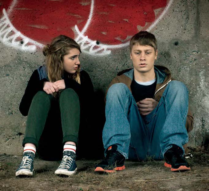 Image du film 1:54 montrant deux adolescents assis l'un à côté de l'autre; une fille à gauche et un garçon à droite.