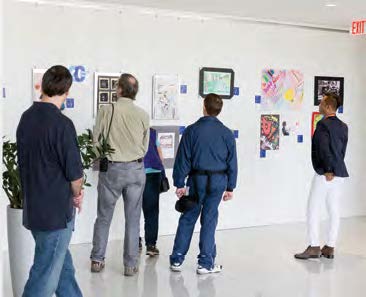 Photo de visiteurs en train d'admirer des travaux artistiques d'élèves affichés sur les murs de l'Ordre