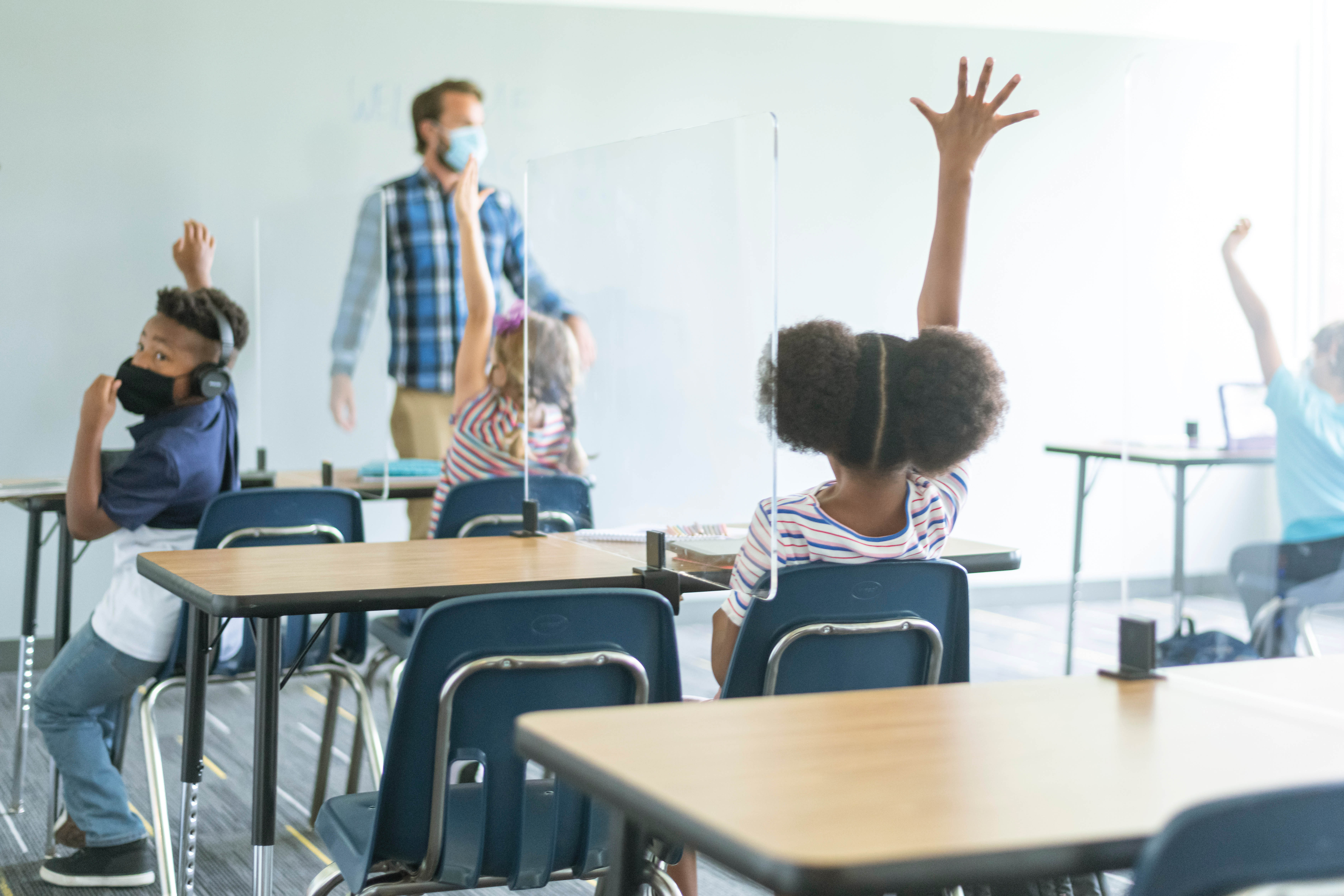 Un enseignant et des élèves portant un masque en classe.