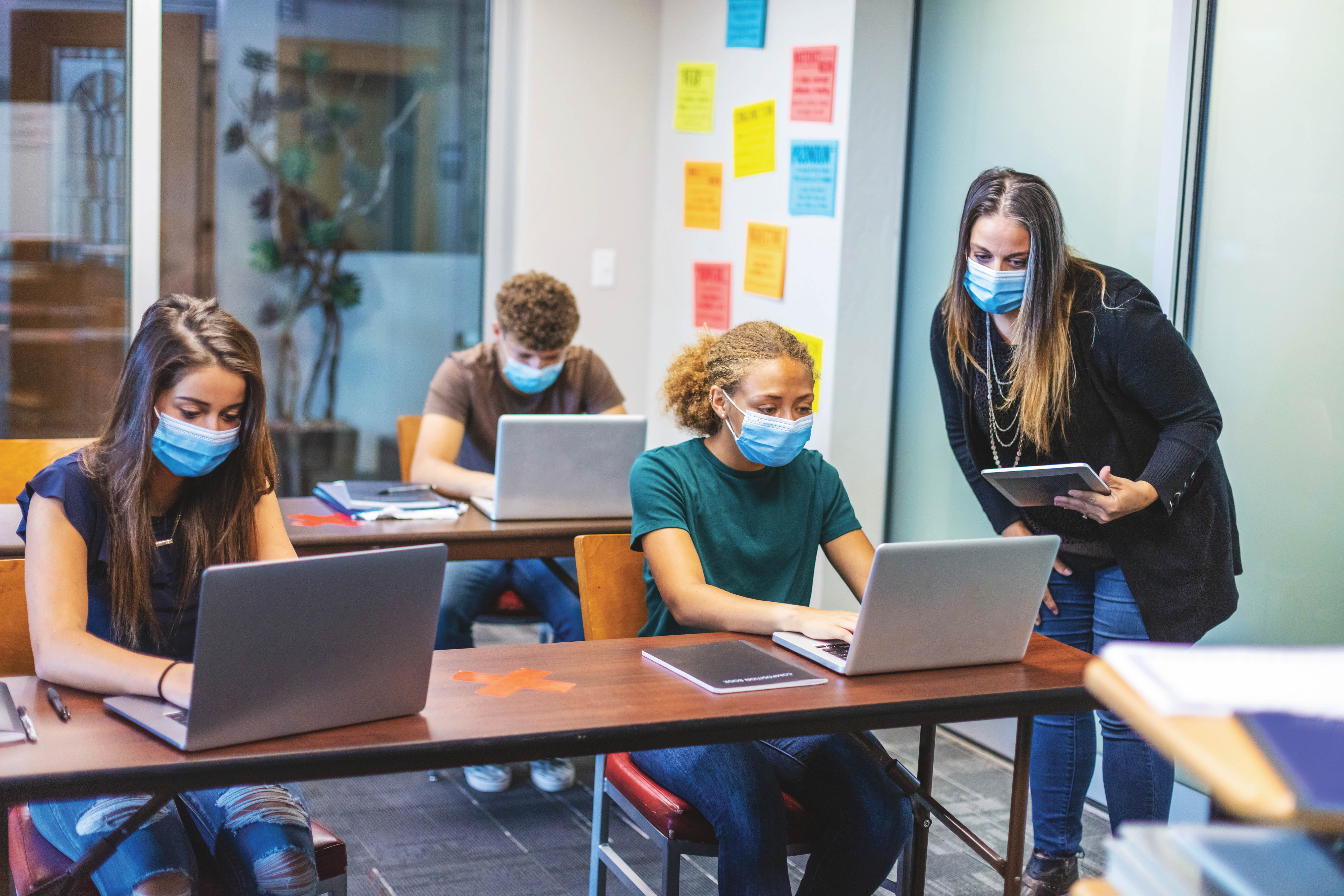 Une enseignante et des élèves portant un masque en classe.