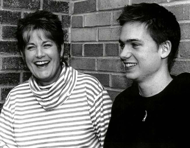 Photo de Patrick J. Adams, acteur, en compagnie de Deborah Barton-Moore, son ancienne enseignante de théâtre. La photo a été prise en noir et blanc, devant un mur de briques.