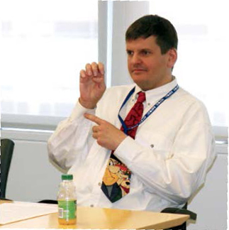 Photo d’un homme qui utilise la langue des signes pendant un atelier sur la QA Enseignement aux élèves ayant une surdi-cécité.