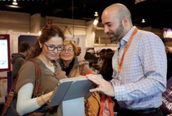Photo de Paul Di Ianni, agent de relations extérieures, qui montre à une participante du Baby Time Show comment s’inscrire au cyberbulletin de l’Ordre.