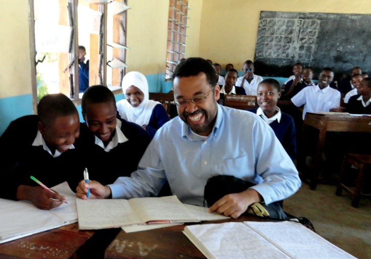 Photo de Lennox Whitehead, pédagogue pour Teachers for Tanzania, assis dans une salle de classe, avec des élèves.