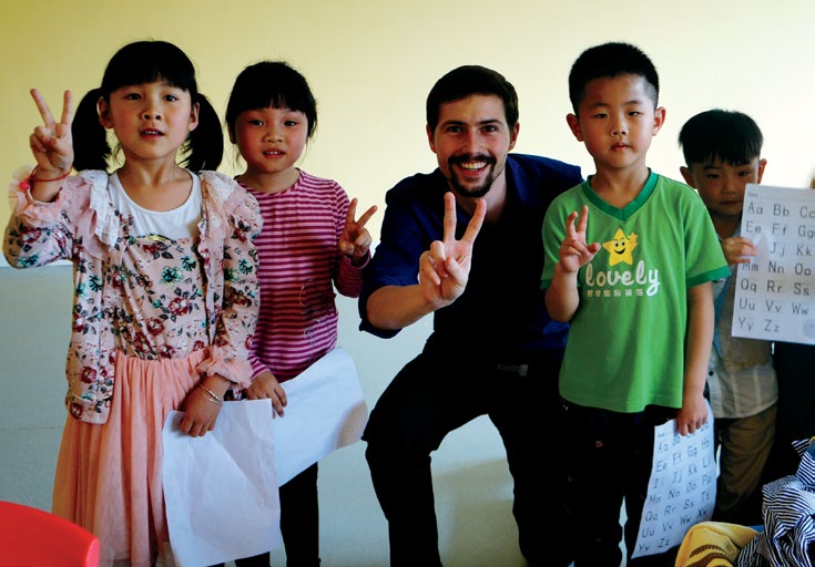 Photo de Josh Rose, enseignant agréé de l’Ontario, avec des élèves à Chongqing (Chine). Ils font tous le V de la victoire avec leurs doigts.