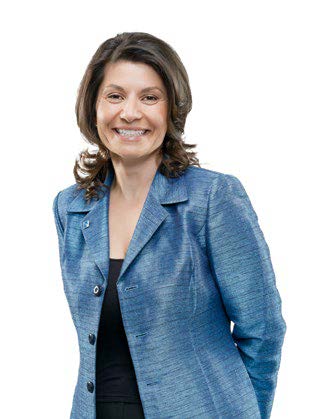 Photo de Liz Papadopoulos, présidente du conseil, debout et souriante, les mains derrière le dos.