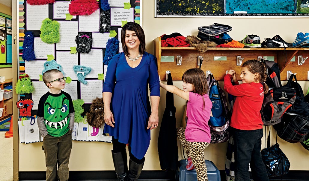 Photo d’Anne-Marie Pinsonneault, debout dans sa salle de classe avec trois élèves.