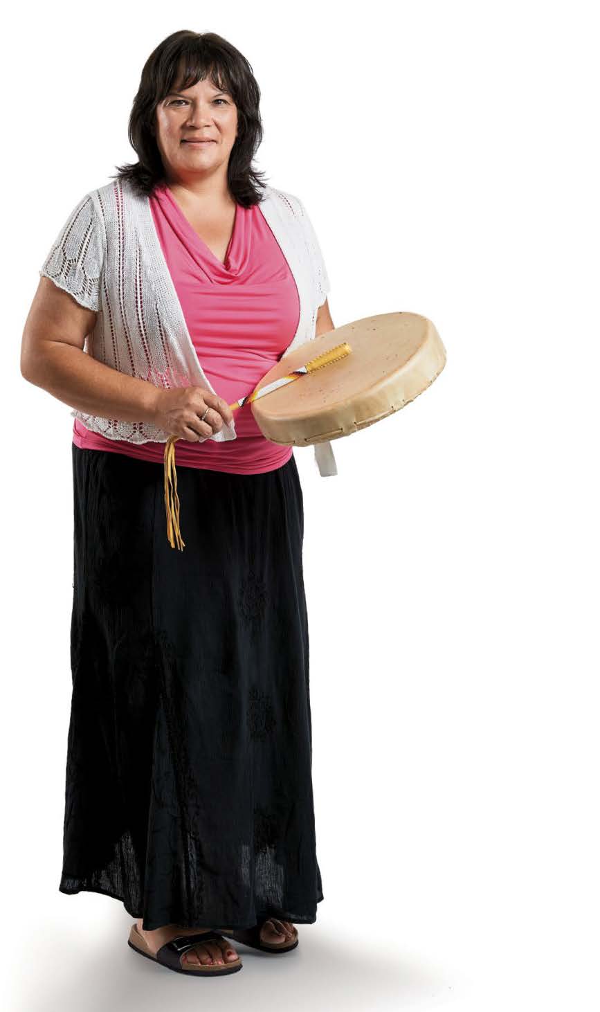 Photo de Debbie Debassige, enseignante agréée de l’Ontario. Elle est d’ascendance autochtone et se tient debout avec un tambour traditionnel en main.
