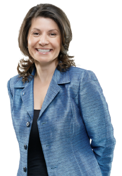 Photo de Liz Papadopoulos, présidente du conseil, debout et souriante, les mains derrière le dos.