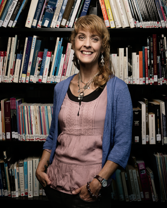 Photo de Julie Godin Morrison, enseignante agrée de l’Ontario, debout devant des étagères de bibliothèque.