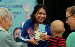 Photo d’un membre du personnel de l’Ordre. Elle sourit à un bébé et à ses parents à la Baby Expo de London.