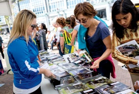 Photo d’un membre du personnel de l’Ordre, une revue à la main. Deux autres personnes regardent les exemplaires de revues offertes sur la table lors du festival The Word on the Street.