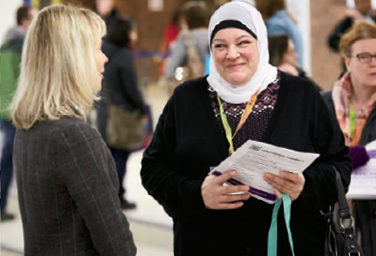Photo d’un membre du personnel de l’Ordre. Elle parle avec une mère à l’occasion d’une conférence organisée pour les parents par le conseil scolaire d’Ottawa-Carleton.