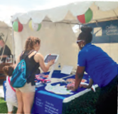 Photo d'un membre du personnel de l’Ordre qui répond aux questions d’une participante utilisant un écran tactile au festival Barrie Waterfront.