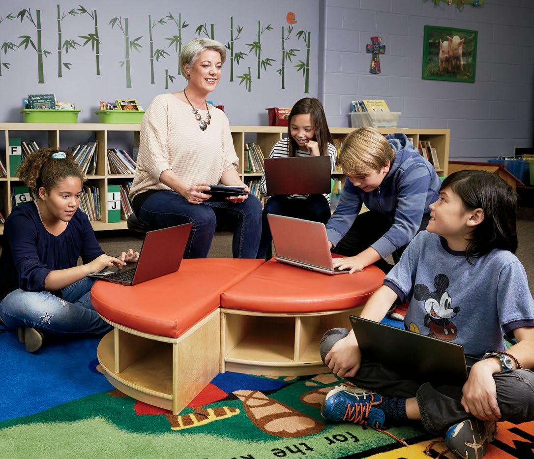 Photo de Jennifer King, enseignante agréée de l’Ontario, assise avec des élèves qui utilisent des ordinateurs portables.
