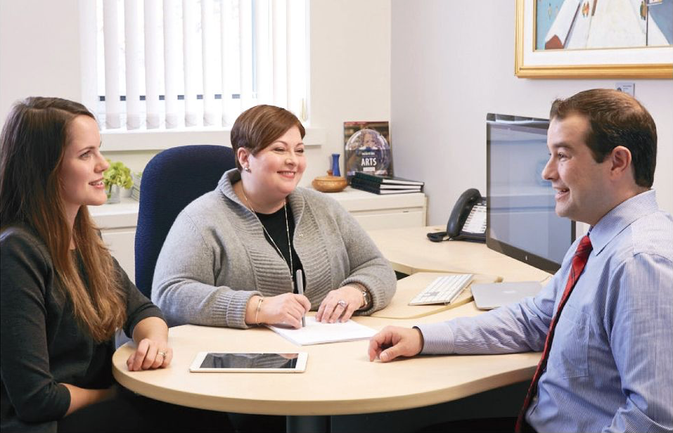 Photo de Sylvie Lamoureux en compagnie de collègues. Elle est assise à son bureau de l’Université d’Ottawa.