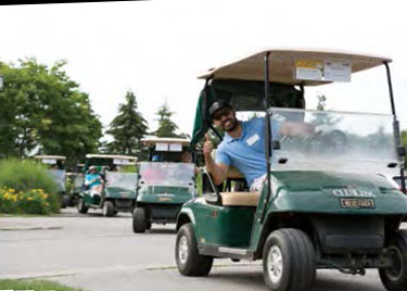 Un golfeur sourit en levant le pouce en signe de victoire, à bord d'une voiturette de golf 