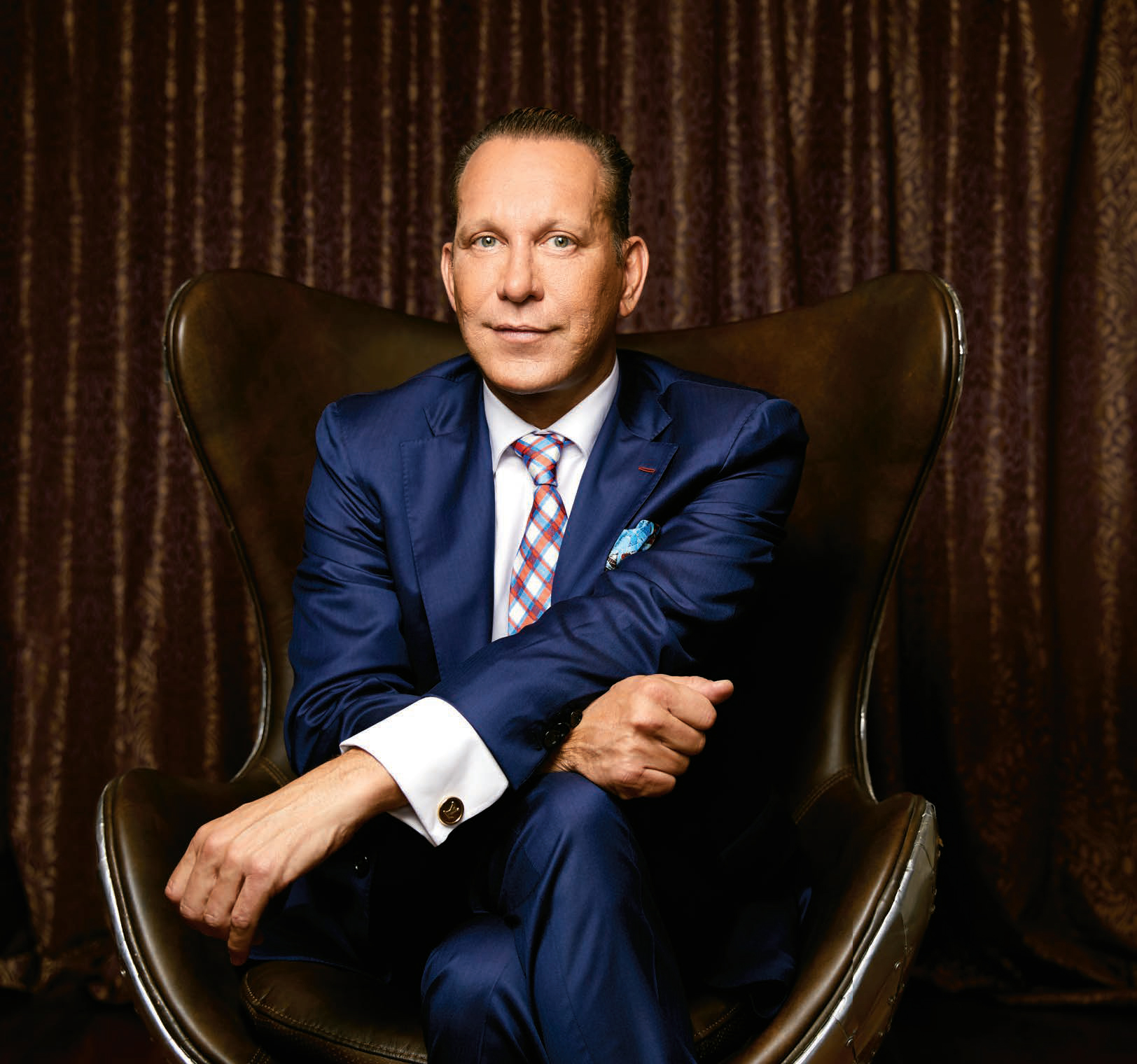 Photo de Michael Wekerle, entrepreneur et vedette de l'émission télévisée Dragon's Den, en costume-cravate, assis sur une chaise.  