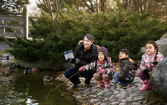 Photo de Laurel Fynes, enseignante agréée de l'Ontario, accroupie au bord d'un ruisseau avec trois élèves.