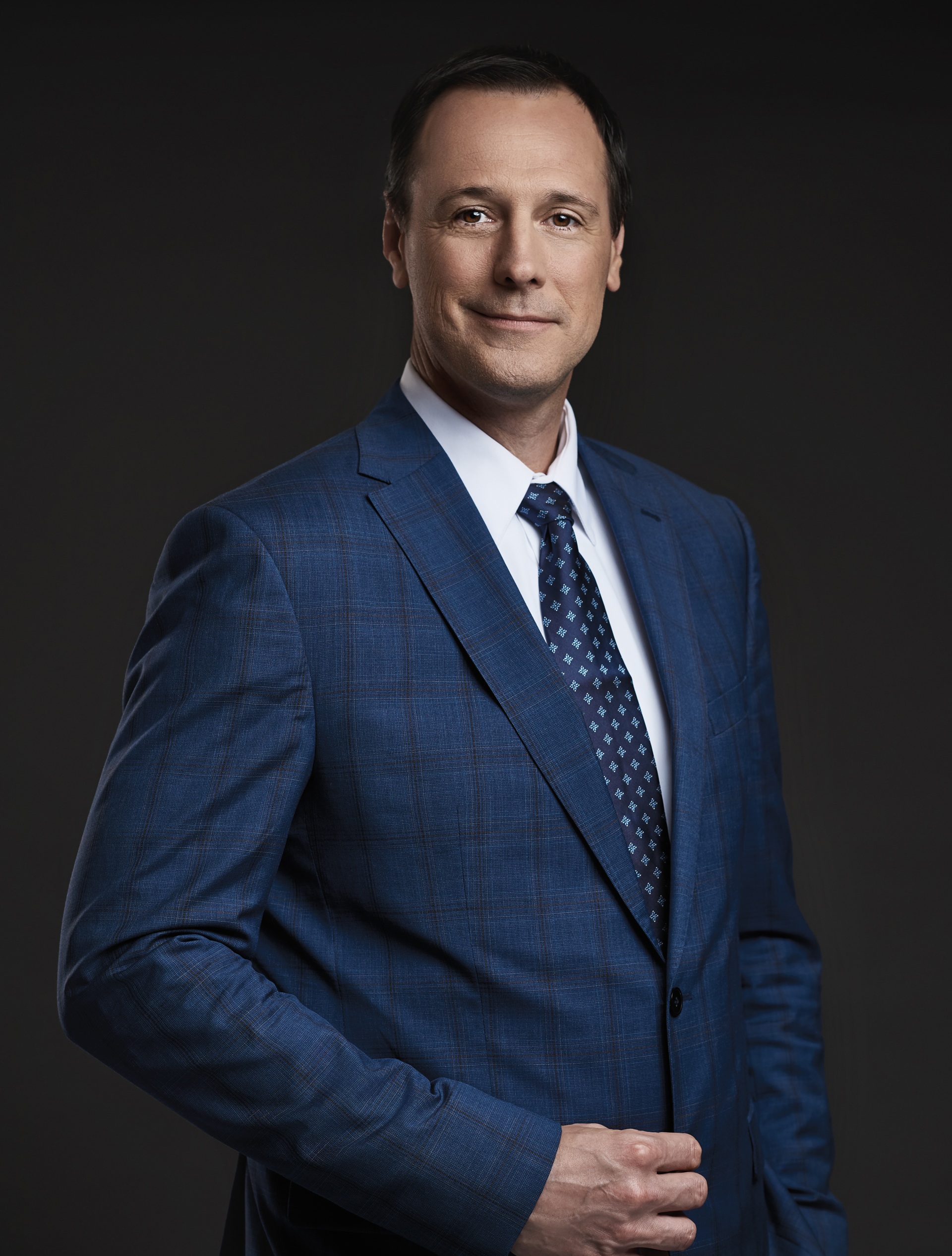 Photo de Jean-François Roberge, ministre de l'Éducation et de l'Enseignement supérieur du Québec, en costume-cravate, debout et souriant. Sa main droite est posée sur son veston.