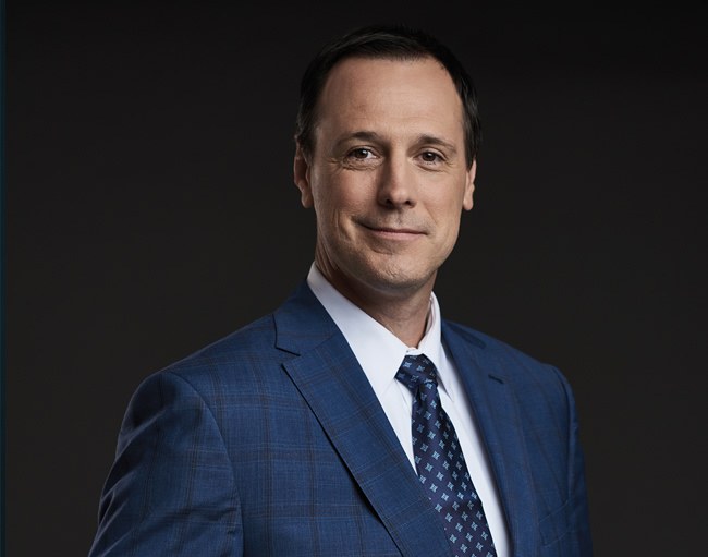 Photo de Jean-François Roberge, ministre de l'Éducation et de l'Enseignement supérieur du Québec, en costume-cravate, debout et souriant. Sa main droite est posée sur son veston.