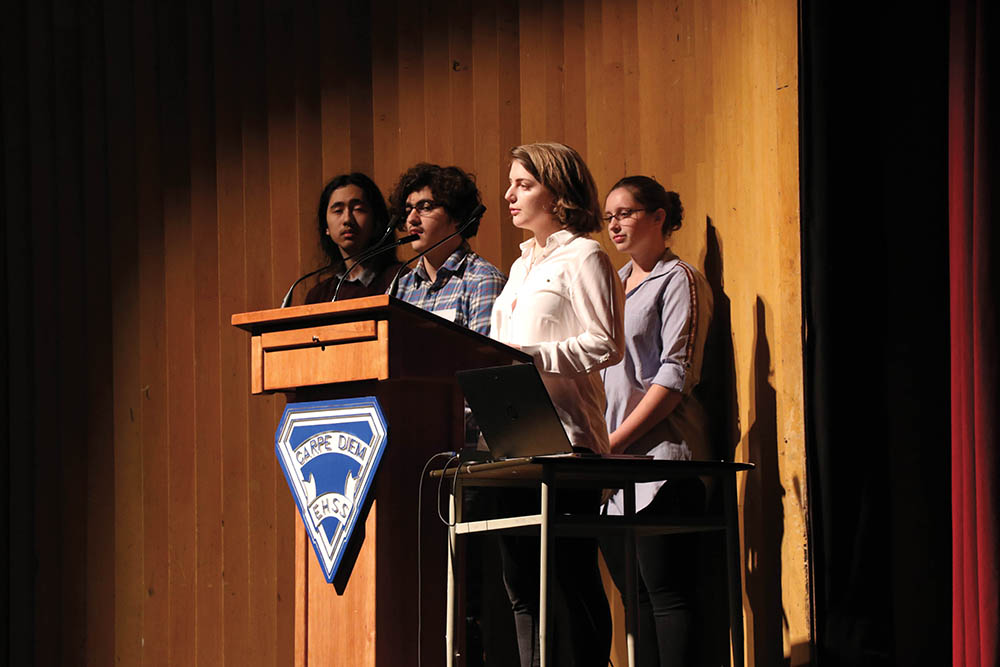 Image de quatre élèves sur un podium dans un auditorium