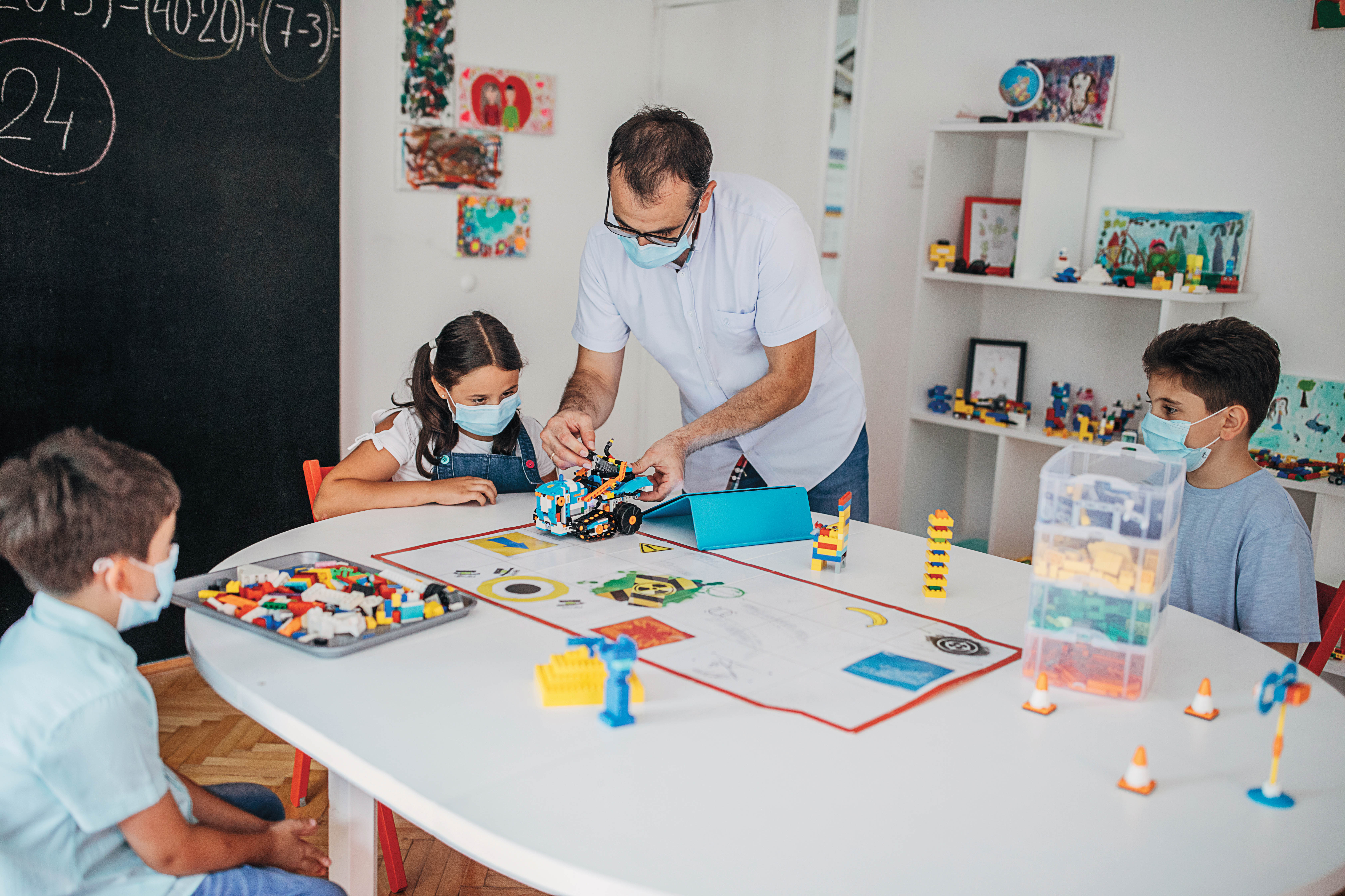 Un enseignant et des élèves apprenant avec des Lego en classe.