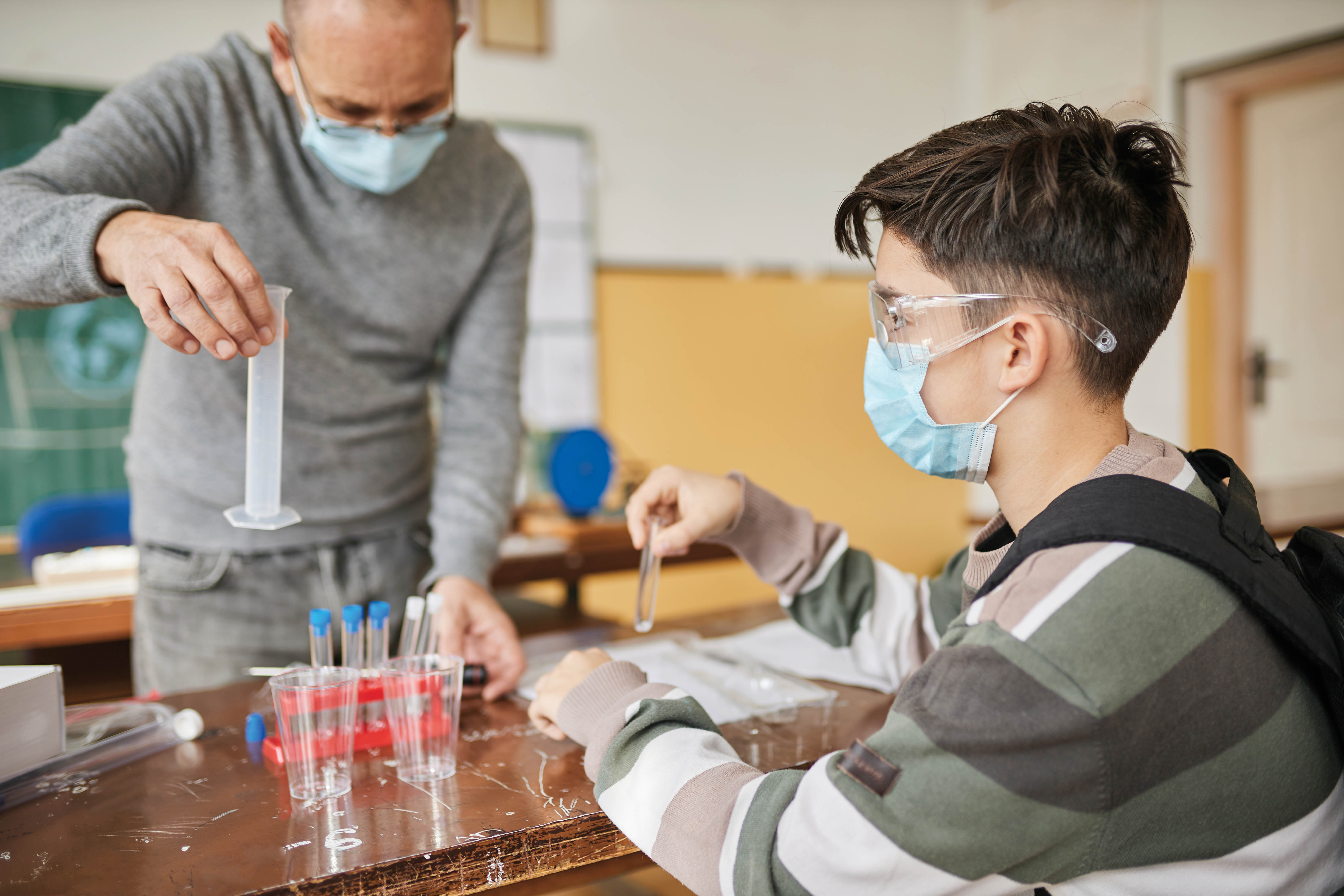 Un élève et un enseignant portant un masque durant un cours de sciences.