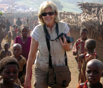 A photo of Sally Armstrong standing surrounded by children.