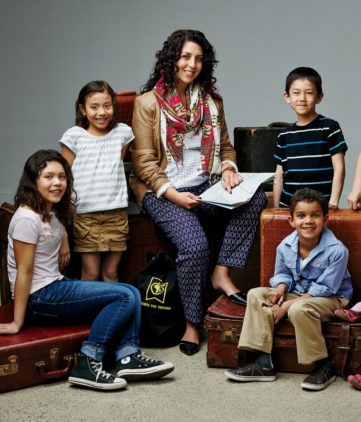Elisa Graceffa surrounded by young students. They are all sitting on a collection of old luggage.