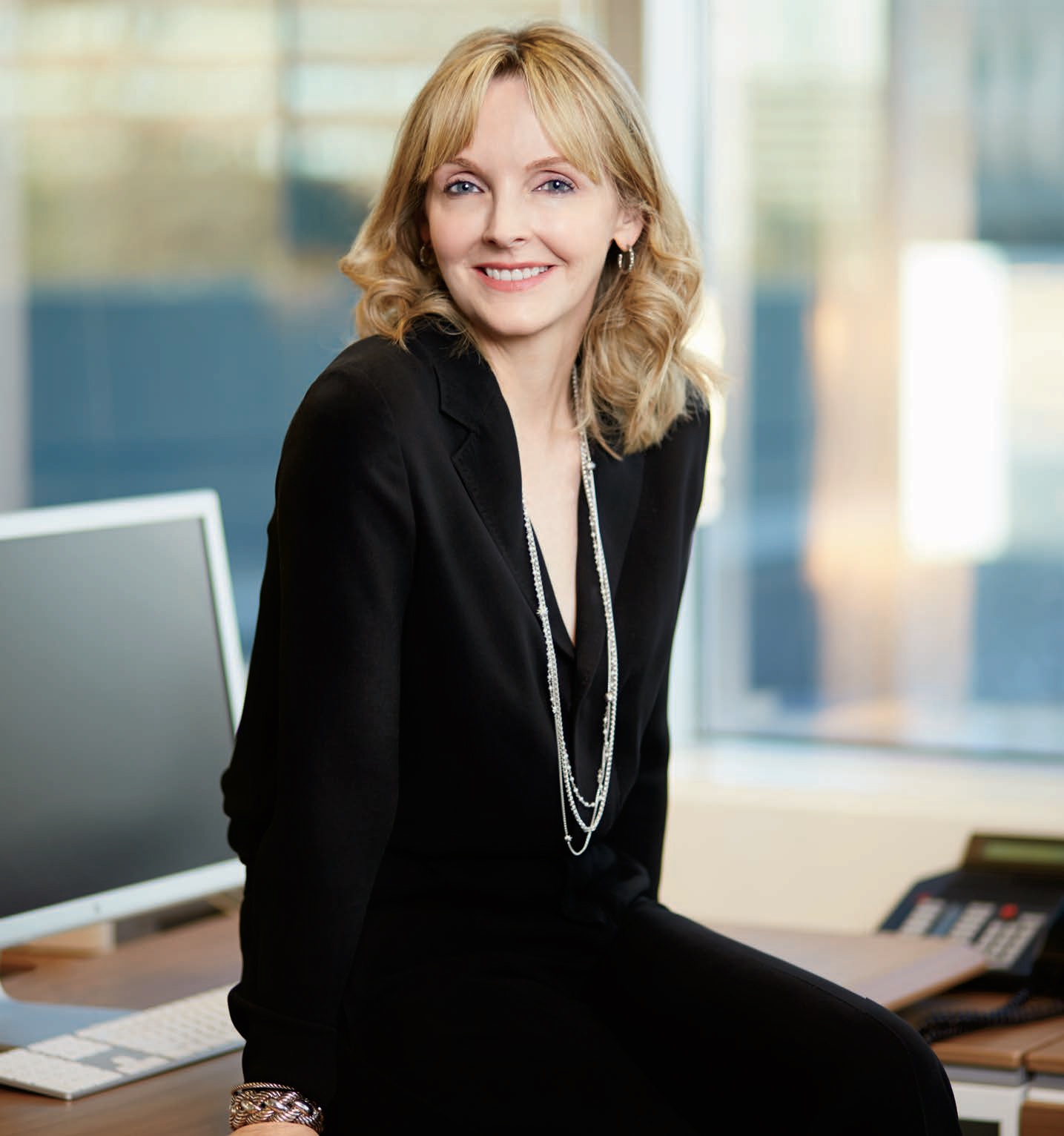 Kirstine Stewart sitting on a desk.