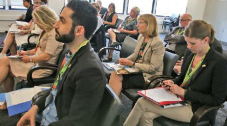 A group of delegates from Sweden are seated watching a presentation about the Ontario College of Teachers.