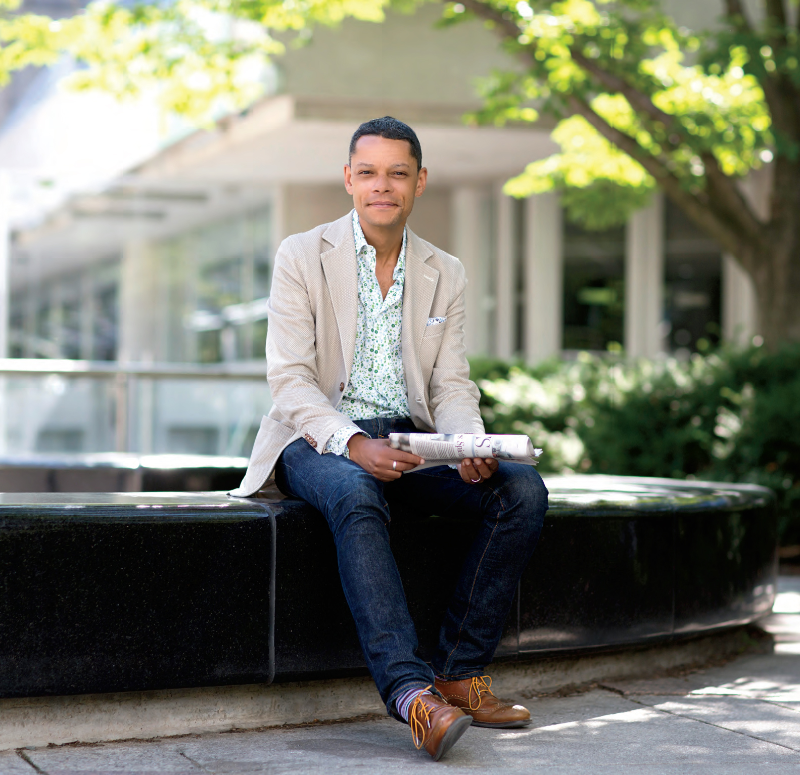A photo of CBC Radio host Matt Galloway seated outside and holding a newspaper.