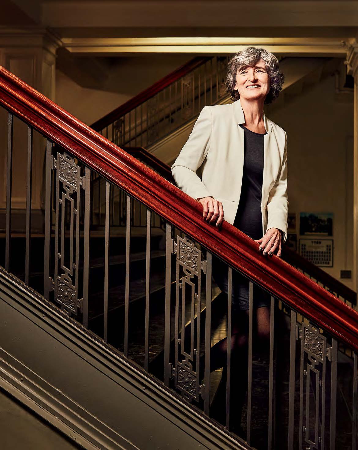 Photo of Helen Wolfe standing on a staircase and smiling.