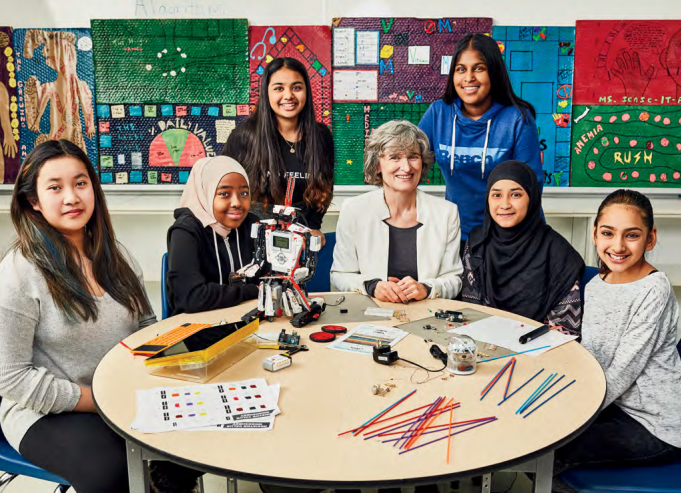 Photo of Helen Wolfe, Ontario Certified Teacher seated at a table surrounded by students.
