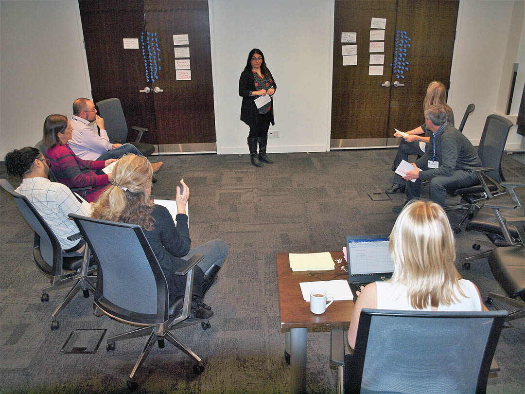 Photo of a person presenting at the front of the room, capturing the attention of a seated audience