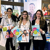 Photo of three people holding College materials.